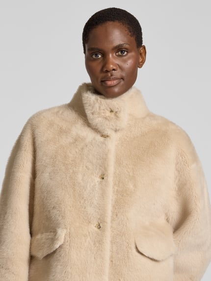 Frauenmodel trägt Regular Fit Webpelzjacke mit Stehkragen von JOOP! in Beige, unifarbenes Kunstfell, Zierknöpfe, Nahaufnahme Oberkörper.