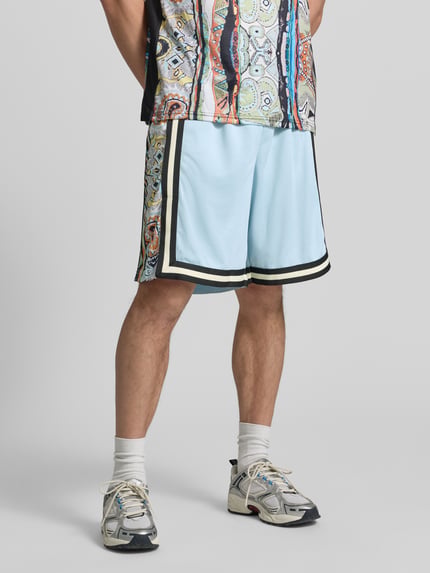 Männermodel trägt Shorts aus Mesh mit Kontraststreifen von COLUCCI in Hellblau mit geradem Schnitt, elastischem Bund, Ganzkörperansicht von vorne.