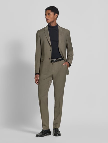 Männermodel trägt Straight Fit Hose mit Lanawoll-Anteil Modell 'Tenuta' von Tiger of Sweden in Beige mit Bügelfalten, Ganzkörperansicht von vorne. Elastischer Material-Mix, Haken- und Reißverschluss, Bundweite 44 cm, Innenbeinlänge 81 cm.