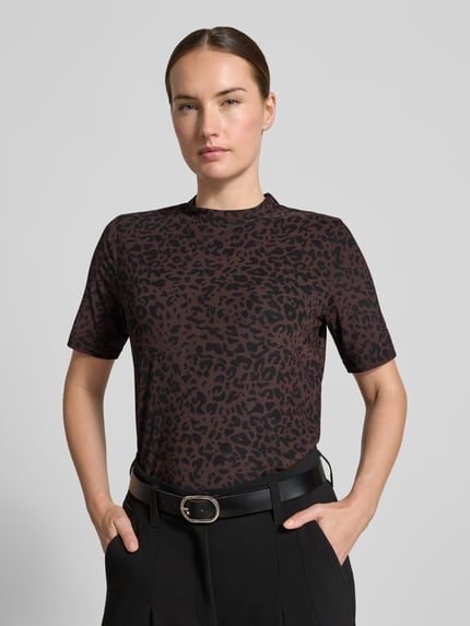 Frauenmodel trägt T-Shirt mit Leo-Print von MORE & MORE, braun-schwarze Muster, gerader Schnitt, Nahaufnahme Oberkörper, Material-Mix mit Stretch-Anteil, Stehkragen, Rückenlänge bei Größe 36: 54 cm.
