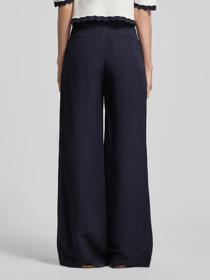 Frauenmodel trägt Wide Fit Stoffhose aus Viskose-mix mit Leinen-Anteil von Marc Cain, kieszenie z wypustkami, wpuszczane kieszenie, detal z logo, mieszanka wiskozy i lnu, szerokość w rozmiarze 36: 37 cm, długość wewnętrzna nogawki 82 cm, całkowity widok z tyłu