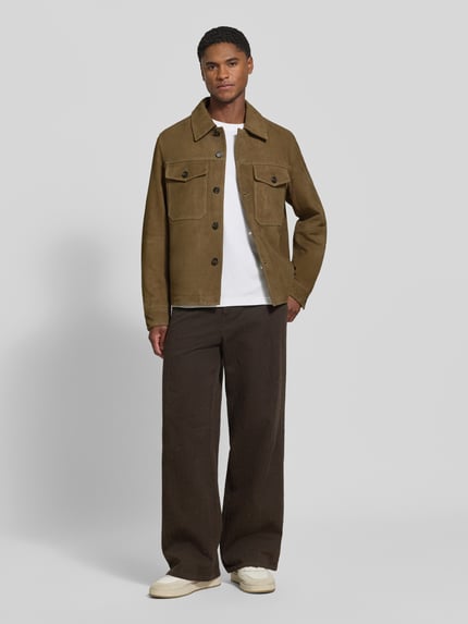 Männermodel trägt Regular Fit Lederjacke aus echtem Ziegenleder Modell 'THOM' von Selected, Erdtöne, glatte Oberfläche, Ganzkörperansicht von vorne. Herren Leder- / Kunstlederjacke von Selected.