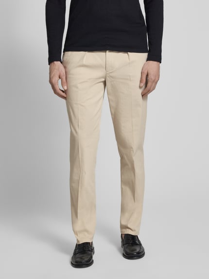 Męski model nosi Hose mit Bügelfalten und Gesäßtaschen von Profuomo, mieszanka bawełny i elastanu, krój relaxed fit, kanty, kieszenie z tyłu, szerokość w rozmiarze 50: 46 cm, długość wewnętrzna nogawki 83 cm, jasny beż, gładka faktura, całkowity widok z przodu.
