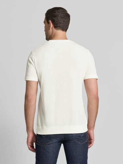 Männermodel trägt Regular Fit T-Shirt aus Baumwoll-Mix von s.Oliver RED LABEL in Creme, schlichte Struktur, Ganzkörperansicht Rückansicht.