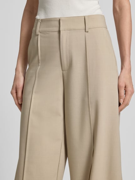 Vrouwenmodel draagt Barrel Fit Hose mit Längsnähten Modell 'Pija' van mbyM in beige met zichtbare lengtenaden, mix van viscosemateriaal, detailopname bovenlichaam.