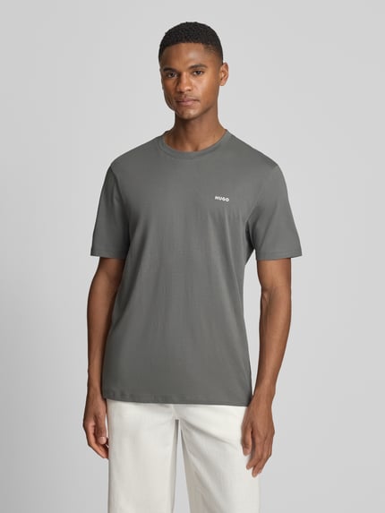 Męski model nosi Regular Fit T-Shirt aus reiner Baumwolle Modell 'DERO222' von HUGO, efekt: jednolity kolor, nadruk z logo, okrągły dekolt, krótki rękaw, dżersej, czysta bawełna, Ganzkörperansicht von vorne.