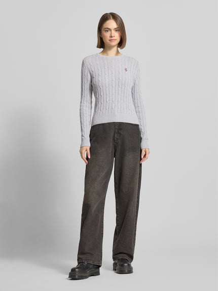 Vrouwenmodel draagt gebreide pullover met kabelpatroon en labelstitching van REVIEW, katoenmix, regular fit, ronde hals, Ganzkörperansicht van voren.