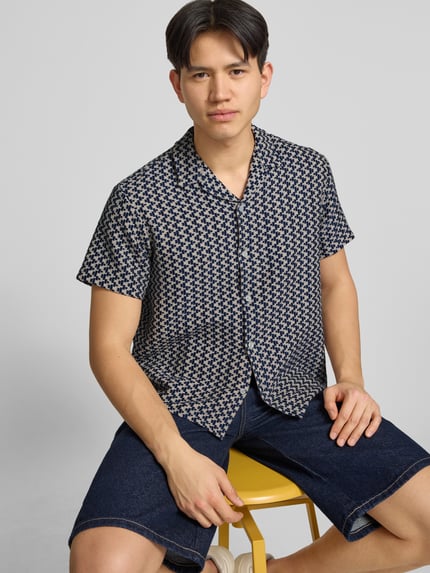 Männermodel trägt Regular Fit Freizeithemd im Allover-Look Modell 'MONTAUK' von Jack & Jones in Blau mit Knopfleiste, Nahaufnahme Oberkörper. Material-Mix mit Baumwoll-Anteil, Reverskragen, kurze Ärmel.