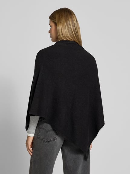 Frauenmodel trägt Poncho mit asymmetrischem Saum von PIECES, unifarbenes Strickmaterial, hochgeschlossen, Ganzkörperansicht Rückansicht.