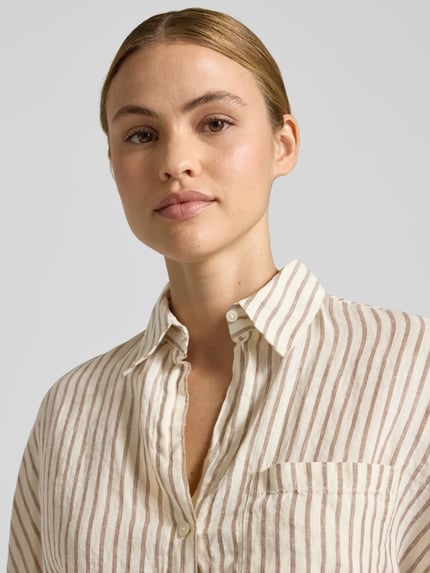 Frauenmodel trägt Relaxed Fit Kurzarmbluse aus reinem Leinen von Marc O'Polo mit gestreiftem Allover-Muster, Nahaufnahme Oberkörper.