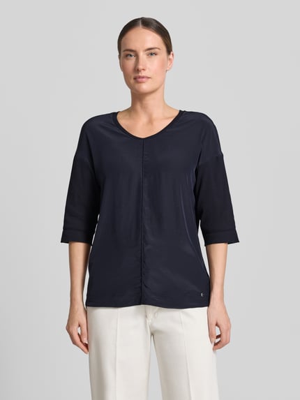 Frauenmodel trägt T-Shirt mit Ärmelaufschlag und Rundhalsausschnitt von Marc Cain, damski t-shirt z mieszanki bawełny z dodatkiem streczu, krój straight fit, okrągły dekolt, zakładka na rękawach, detal z logo, długość tyłu w rozmiarze 36: 62 cm, Ganzkörperansicht von vorne