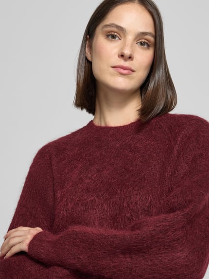 Frauenmodel trägt Pullover aus Mohair mit geripptem Abschluss von Selected in Unifarbe Bordeaux, Stricktextur, Rundhalsausschnitt, Nahaufnahme Oberkörper.