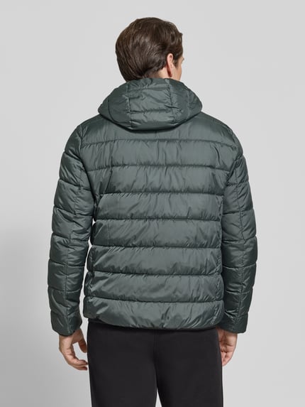 Männermodel trägt Steppjacke mit Kapuze und Reißverschluss von MCNEAL in dunklem Grün, glatte Textur, Ganzkörperansicht Rückansicht. Herren Steppjacke von MCNEAL, Regular Fit, Rückenlänge 70 cm, Schulterbreite 46 cm, Brustweite 54 cm, Ärmellänge 63 cm.