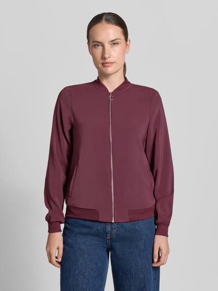 Vrouwenmodel draagt Regular fit blouson met ritssluitingdetail van VERO MODA, Dames bomberjack, effen bordeauxrood, gladde textuur, geheellichaamsvooraanzicht.