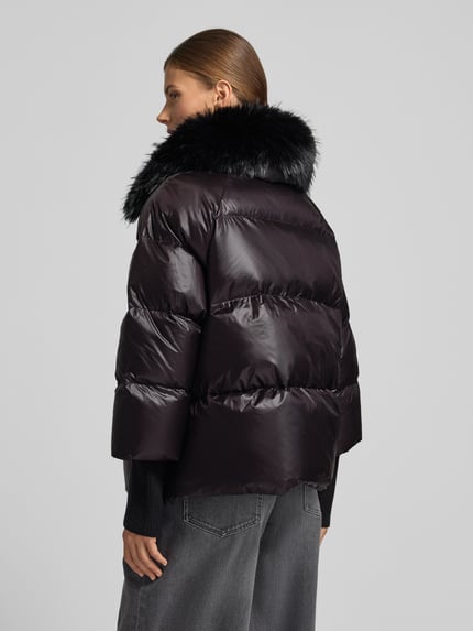 Kobiece modelka nosi czarną, błyszczącą Steppjacke mit Kunstfell Modell 'Mila' od ROCKANDBLUE, krój regular fit, szerokość w rozmiarze 36: 58 cm, z krytym zamkiem i kieszeniami na zamek, długość pleców w rozmiarze 36: 61 cm, szerokość ramion w rozmiarze 36: 43 cm, długość rękawa w rozmiarze 36: 46 cm, widok całej sylwetki od tyłu