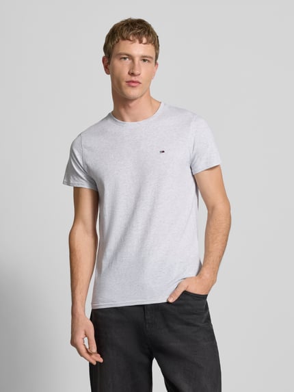 Männermodel trägt Regular Fit T-Shirt aus reiner Baumwolle von Tommy Jeans, Optik: Melange, Logo-Stitching, Nahaufnahme Oberkörper.
