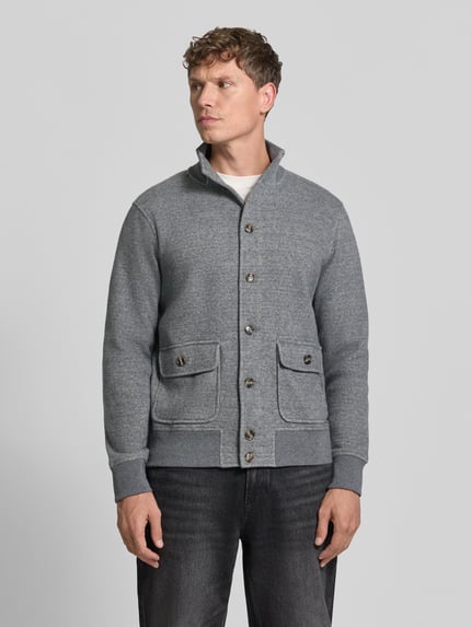 Männermodel trägt Strickjacke aus Wolle mit Stehkragen von RAGMAN in Grau-Melange mit Strukturmuster, Pattentaschen, Ganzkörperansicht von vorne.