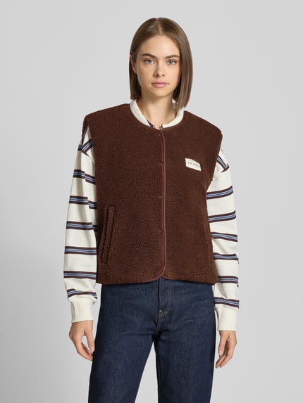 Kobiece modelka nosi kamizelkę Regular Fit Weste aus reiner Baumwolle Model 'Magnolia' od OH APRIL z futerkiem, brąz, naszywka z logo, krój regular fit, bawełna, Długość tyłu w rozmiarze S: 56 cm, Szerokość ramion w rozmiarze S: 43 cm, Szerokość klatki piersiowej w rozmiarze S: 48 cm, Ganzkörperansicht von vorne.