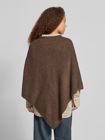 Frauenmodel trägt Poncho mit asymmetrischem Saum von PIECES in brauner Melange-Strickoptik, über karierte Bluse und Jeans, Ganzkörperansicht Rückansicht.