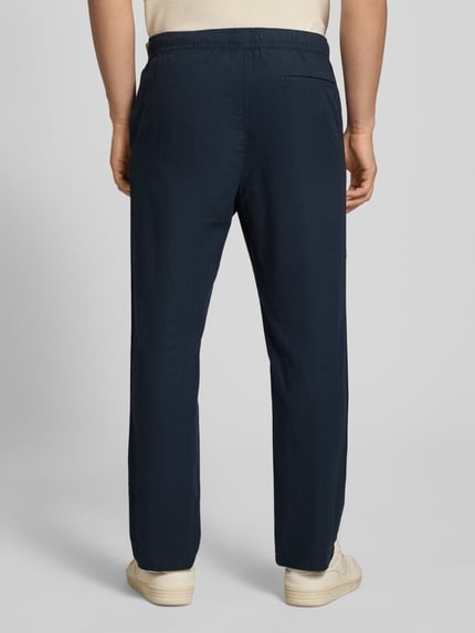 Männermodel trägt Pull On Hose in Leinen-Optik mit Eingrifftaschen von REVIEW in Dunkelblau, elastischer Bund, Gesäßleistentasche, Ganzkörperansicht Rückansicht.