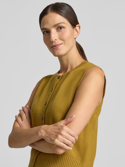 Frauenmodel trägt Strickweste aus Viskose-Mix mit Knopfleiste von Christian Berg Woman in Senfgelb, feine Struktur, Nahaufnahme Oberkörper. Regular Fit, Rundhalsausschnitt, Rückenlänge bei Größe S 49 cm.