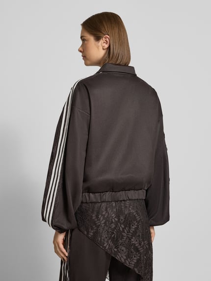 Männermodel trägt Oversized Sweatjacke aus Baumwoll-Mix Modell 'LACE OVERSIZED' von adidas Originals in Schwarz mit weißen Streifen, Strukturmix, Ganzkörperansicht Rückansicht.