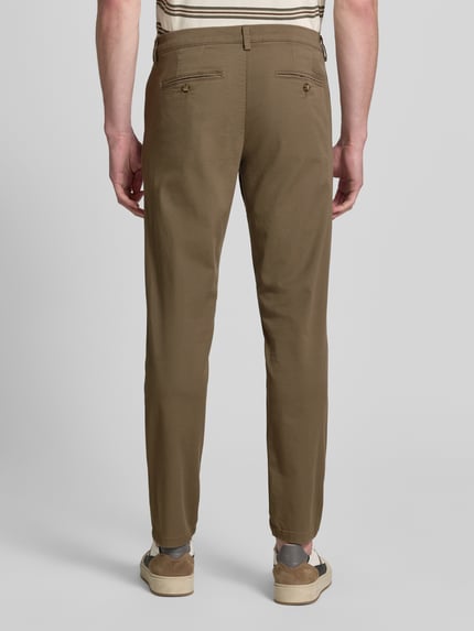 Männermodel trägt Slim Fit Chino aus Baumwoll-Mix Modell 'MILES' von Selected Homme in Unifarbe mit Gesäßtaschen, Ganzkörperansicht Rückansicht.