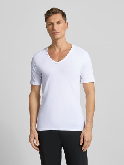 Męski model nosi T-shirt mit V-Ausschnitt von MCNEAL, mieszanka bawełny z dodatkiem streczu, krój regular fit, szwy działowe, biała gładka textura, Ganzkörperansicht von vorne.