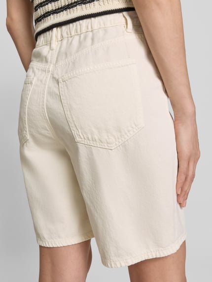 Modelka nosi Regular Fit Bermudas aus Baumwoll-Lyocell-Mix Modell 'VILLA' von Vero Moda, beżowy denim, 5 kieszeni, detal tunel w pasie, zdjęcie całej sylwetki z tyłu.