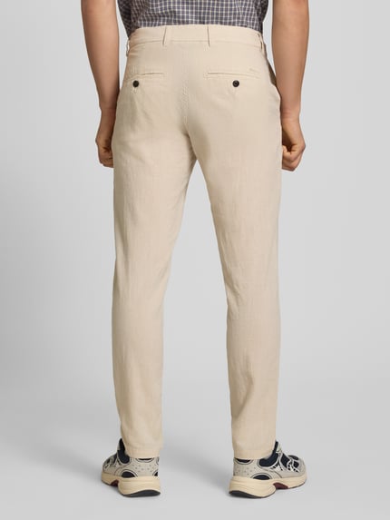 Mężczyznamodel nosi spodnie Tapered Fit Hose mit Eingrifftaschen Modell 'STACE' von Jack & Jones, mieszanka materiałów z bawełną, krój tapered fit, wpuszczane kieszenie, szerokość w rozmiarze 32/32: 45 cm, długość wewnętrzna nogawki: 77 cm, jasny kolor, gładka tekstura, widok całopostaciowy z tyłu.