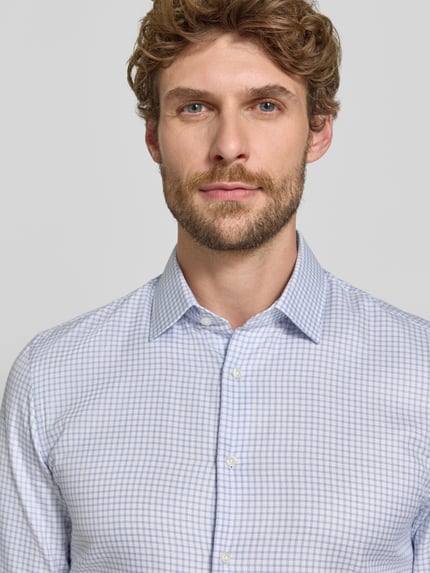 Männermodel trägt Super Slim Fit Businesshemd aus reiner Baumwolle von Jake*s, feines Karo-Muster in hellblau und weiß, Nahaufnahme Oberkörper.