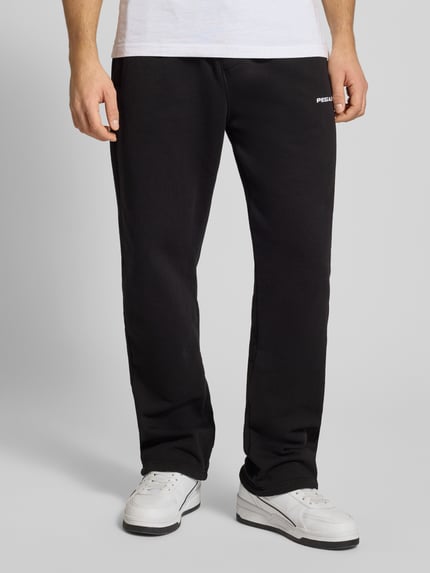 Männermodel trägt Sweatpants mit elastischem Bund von Pegador aus schwarzem Baumwoll-Mix, Label-Stitching, französische Eingrifftaschen, lockerer Schnitt, Ganzkörperansicht von vorne.