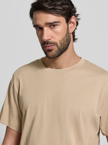 Männermodel trägt Regular Fit T-Shirt aus reiner Baumwolle Modell 'ASPAN' von SELECTED HOMME in Beige, unifarben, Nahaufnahme Oberkörper.