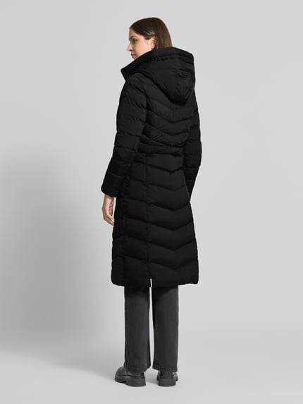 Frauenmodel trägt Steppmantel mit Eingrifftaschen Modell 'INGRAM' von khujo in Schwarz mit Steppnähten und Kapuze, Ganzkörperansicht Rückansicht.