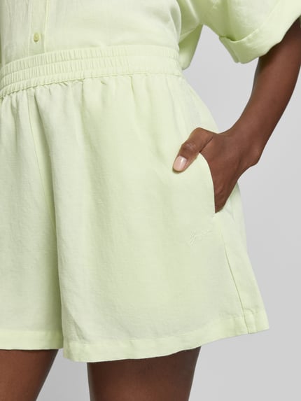 Vrouwenmodel draagt Relaxed Fit Shorts uit linnen-viscosemix model 'TALLAN' van BOSS Orange, uni, elastische tailleband, mid waist, detailopname heup.