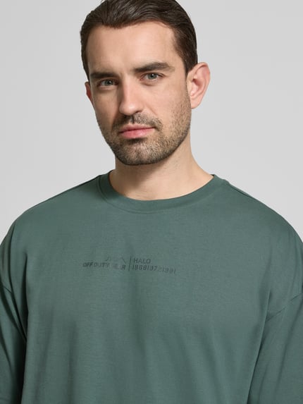 Męski model nosi Boxy Fit T-Shirt mit Rundhalsausschnitt von HALO z bawełny, pudełkowy krój, okrągły dekolt, długość tyłu 71 cm, Nahaufnahme Oberkörper.
