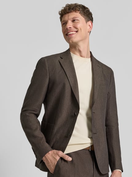 Męski model nosi Slim Fit 2-Knopf-Sakko aus Leinen Modell 'Hoverest' od JOOP! Collection, brązowy lniany materiał, krój slim fit, klasyczny kołnierz, naszywane kieszenie, Szerokość w rozmiarze 50: 49 cm, długość tyłu: 73 cm, długość rękawa: 65 cm, kolor jednolity, tekstura lekko widoczna, całkowity widok z przodu.