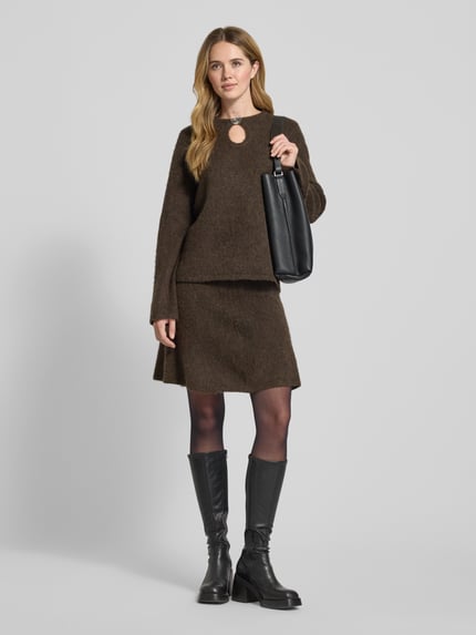 Frauenmodel trägt Relaxed Fit Pullover aus Woll-Mix mit Alpaka-Anteil Modell 'LULU' von Selected Femme in brauner Melange-Optik, Strick, gerippte Abschlüsse, Brosche hinten, Rundhalsausschnitt, überschnittene Schultern, Ganzkörperansicht von vorne.