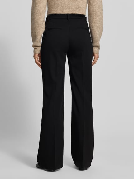 Frauenmodel trägt schwarze Flared Fit Hose mit Viskose-Anteil von MYON, elastischer Material-Mix, Bügelfalten, Ganzkörperansicht Rückansicht.