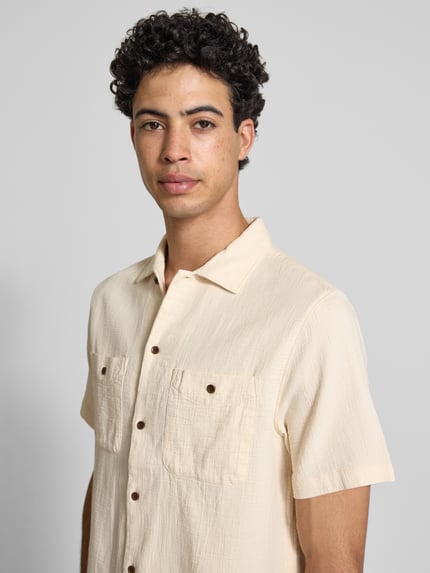 Männermodel trägt Regular Fit Freizeithemd mit Kentkragen und Brusttaschen von Superdry in Creme, Reine Baumwolle, Strukturmuster, Nahaufnahme Oberkörper. Rückenlänge bei Größe M: 70 cm, Schulterbreite 54 cm, Ärmellänge 30 cm.