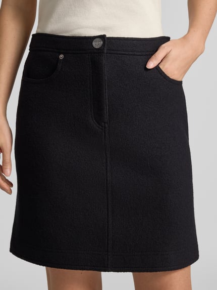 Vrouwenmodel draagt Gerader Mini-Rock aus reiner Schurwolle van Marc Cain in effen zwart met fijne structuur, detailopname heupen en dijen.