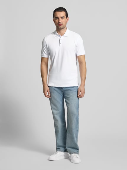 Männermodel trägt Regular Fit Poloshirt mit Logo-Detail Modell 'Pete' von BRAX aus elastischem Baumwoll-Mix, hell, Kurzärmelig, Ganzkörperansicht von vorne.