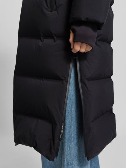 Frauenmodel trägt Regular Fit Daunenmantel mit Kapuze von Marc O'Polo, schwarze Steppoptik und sichtbarer Reißverschluss, Nahaufnahme Unterkörper, Damen Steppmantel von Marc O'Polo