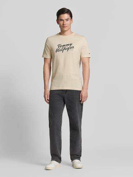 Männermodel trägt Regular Fit T-Shirt aus reiner Baumwolle von Tommy Hilfiger, uni, labelprint, rond hals, korte mouwen, jersey, voorkant, volledige lichaamsweergave.