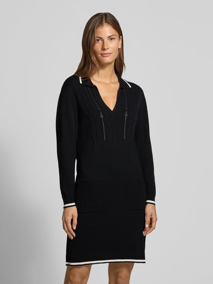 Frauenmodel trägt Knielanges Strickkleid mit Kontraststreifen von Liu Jo, V-Ausschnitt, Polokragen, Zopfmuster, Schwarz mit Weiß, Ganzkörperansicht von vorne.