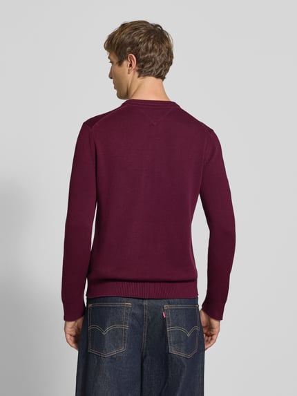 Männermodel trägt Slim Fit Pullover aus reiner Baumwolle von Tommy Jeans in Bordeaux, unifarben, Struktur-Strick, Ganzkörperansicht Rückansicht.