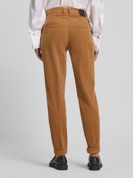 Frauenmodel trägt Cordhose mit aufgeschlagenem Saum von Marc Cain in Camel, feine Rippenstruktur, Slim Fit, Gesäßleistentaschen, Ganzkörperansicht Rückansicht. Baumwoll-Mix mit Stretch-Anteil, Saum mit Aufschlag, französische Eingrifftaschen, Knopf- und Reißverschluss, Bundweite 41 cm, Innenbeinlänge 73 cm bei Größe 36.