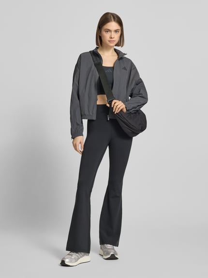 Frauenmodel trägt schwarze Flared Fit Stoffhose mit breitem Bund Modell 'All Me' von adidas Sportswear, elastischer Material-Mix, Ganzkörperansicht von vorne.
