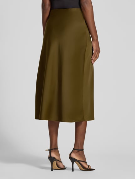Frauenmodel trägt Midirock aus Satin Modell 'PELLA' von YAS in Olivgrün mit A-Linie und elastischem Bund, Ganzkörperansicht Rückansicht. Damen Midirock von YAS, Satin, A-Linie, Modell 'PELLA', elastischer Bund, Bundweite bei Größe S: 37 cm, Gesamtlänge bei Größe S: 82 cm.