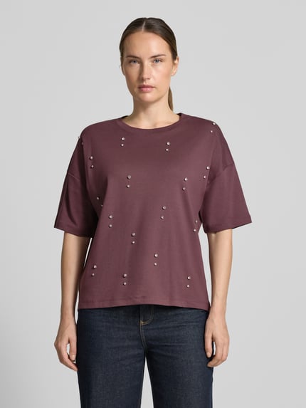 Frauenmodel trägt T-Shirt aus reiner Baumwolle von Christian Berg Woman in lockerem Schnitt mit Ziersteinen, Ganzkörperansicht von vorne.